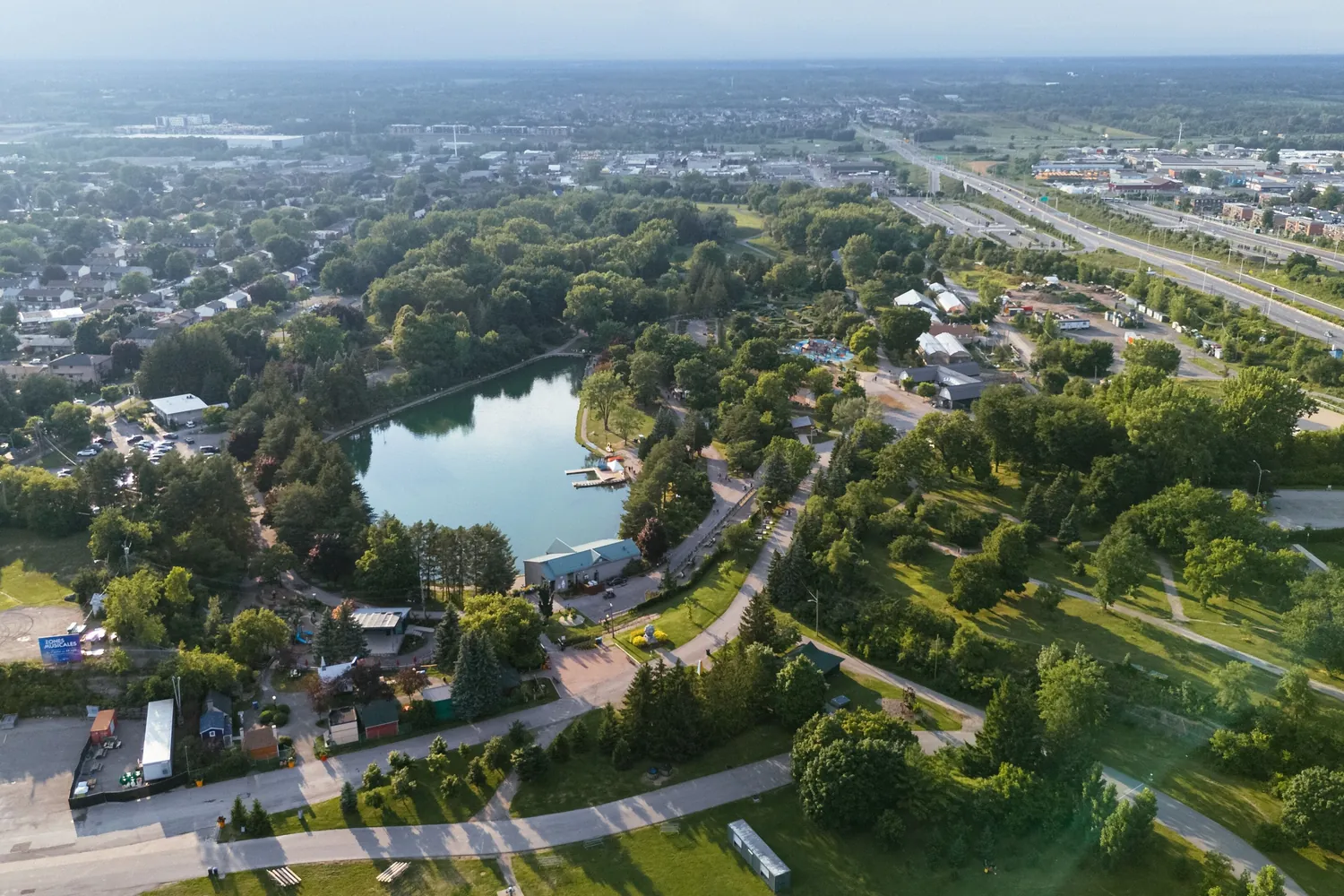 Aerial view of Boisbriand, with a park around a small lake and the highway running along one side