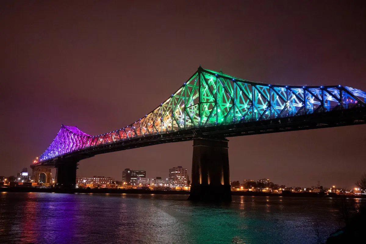 The Jacques Cartier Bridge lit up in colour at night over the St. Lawrence